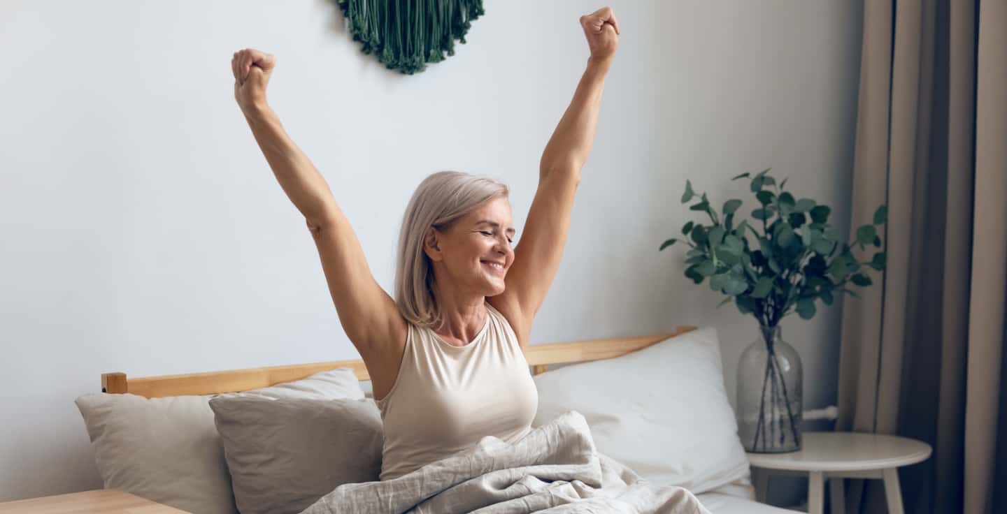 mevrouw zit in bed terwijl ze zich uitstrekt