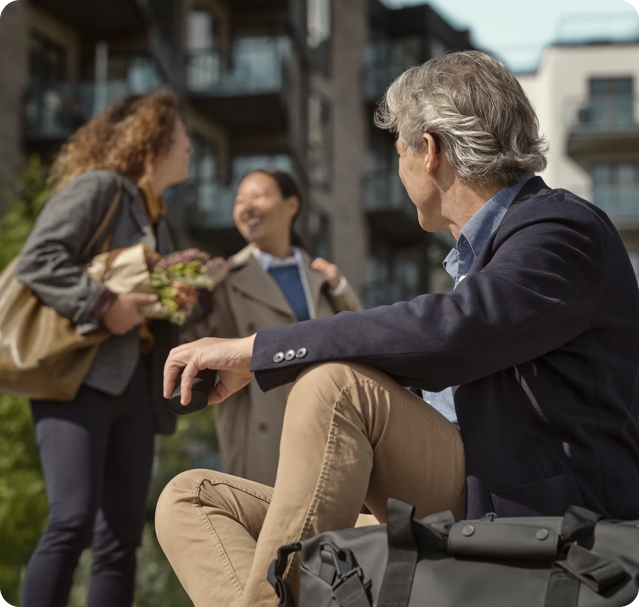 meneer met grijs haar zit terwijl hij praat met twee vrouwen naast hem