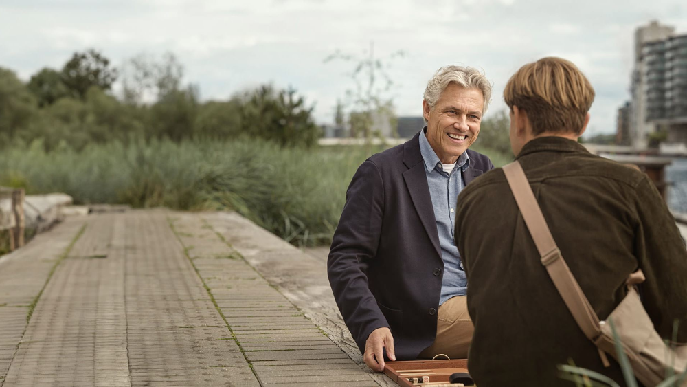 2 mannen zitten op een pier aan het water